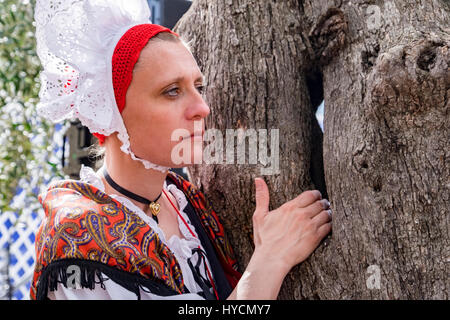 Young woman in traditional costume of old Nice, France, waits for her cue to take the stage at a folk festival Stock Photo