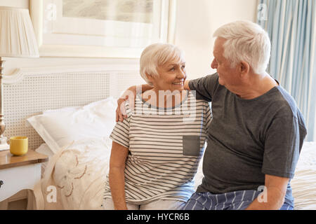 Affectionate senior couple sitting on their bed in the morning Stock Photo