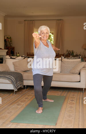 Smiling senior woman in sportswear doing yoga alone at home Stock Photo