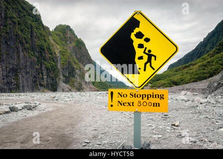 Warning sign telling hikers not to stop due to risk of falling rocks. Stock Photo