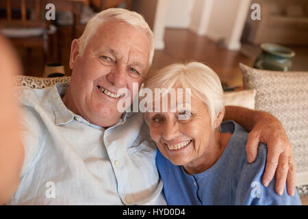 Happy senior couple taking selfies together on their sofa  Stock Photo