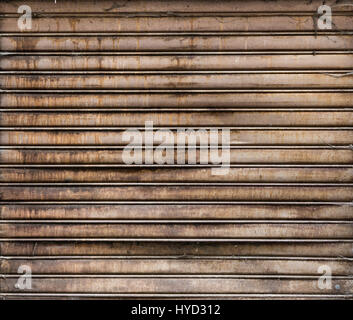 Grungy weathered metallic roll up door. Rusty iron gate. Stock Photo