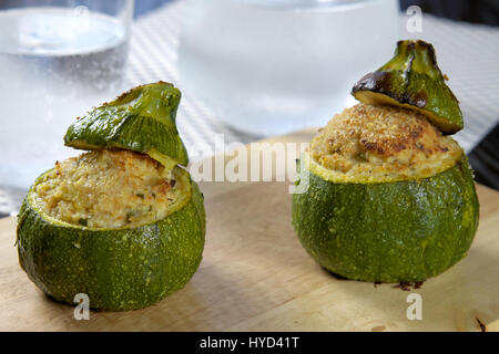 Tuna, bread crumbs and mayonnaise stuffed round zucchini (courgette) with glass and carafe of fresh sparkling water in bokeh background Stock Photo