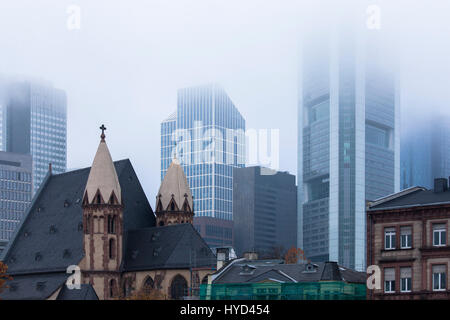 , Germany, Hesse, Frankfurt, St. Leonhards church in front of the skyscrapers of the financial district, fog. Stock Photo