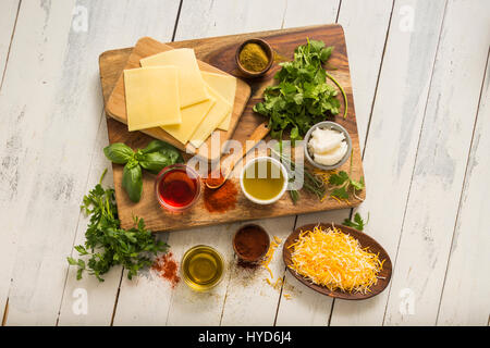 Cheese, herbs and spices on cutting board Stock Photo