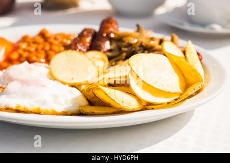 Full English Breakfast including sausages, tomatoes and mushrooms, egg, bacon, baked beans and chips. Stock Photo