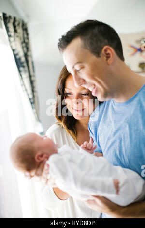 Father carrying daughter (0-1 months) and standing next to mother Stock Photo