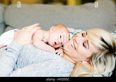 Mother lying on sofa and holding  his one day son (0-1 months) Stock Photo