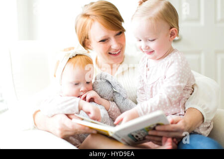 Mother reading book to daughters ( 12-17 months ) Stock Photo