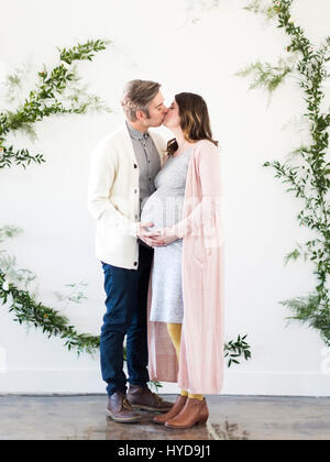 Portrait of men and  pregnant woman kissing Stock Photo