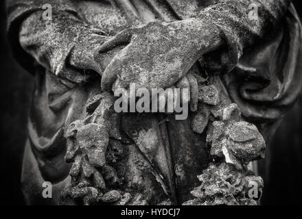 Crossed hands of an angel statue holding a wreath in black and white Stock Photo