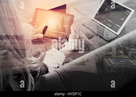 brunette woman using digital talet and laptop computer on sofa in living room with London city exposure Stock Photo