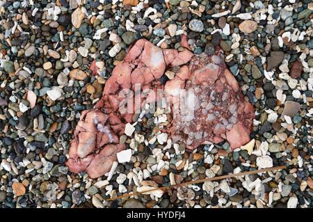 A mixture of stones and coral bits around a pink metamorphic rock along the beach near Suminabang Caves at Caranan, Pasacao, Cam Sur, Philippines. Stock Photo