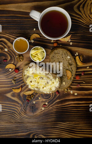 Two slices of bread, cup of tea and a cup of honey and butter, peanuts and decorated with pieces of dried apple lying on a wooden background. Top of v Stock Photo