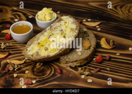 Two slices of bread and a cup of honey and butter, peanuts and decorated with pieces of dried apple lying on a wooden background Stock Photo
