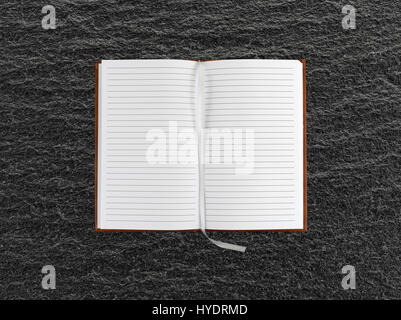 Top view of an opened brown leather journal on a black slate table with blank pages and a cloth bookmark. Stock Photo