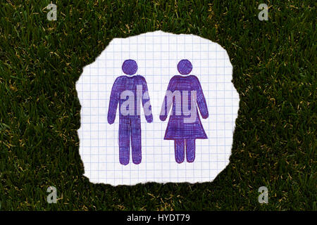 Sheet of checkered paper with hand drawn man and woman figures on grass background. Doodle style. Stock Photo