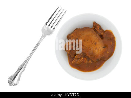 Top view of a bowl with a serving of tilapia fillet in a marinara sauce plus a fork to the side isolated on a white background. Stock Photo