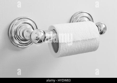 Toilet paper roll on a holder attached to a wall. Stock Photo