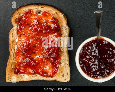 Strawberry Jam or Preserve on Buttered Toast Against a Black Background Stock Photo