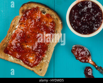 Strawberry Jam or Preserve on Buttered Toast Against a Blue Background Stock Photo