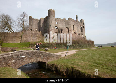 A Man Walking with a guitar in hand over a bridge by Laugharne Castle,The Literary Festival, Laugharne, Wales, Uk Stock Photo