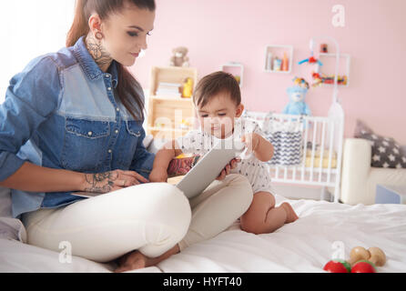 Young mother with baby boy using laptop at home Stock Photo