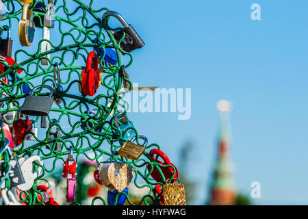 Colorful wedding padlocks on an iron tree. Closeup view. Blurry image of the city tower in the background. Stock Photo