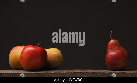 Three apples and one pear on a rustic wooden table, using as background with space for text Stock Photo