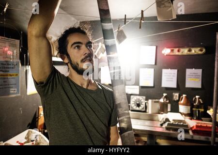 Young man looks at film negatives in a darkroom Stock Photo