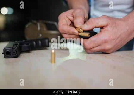 Metal handgun bullet being in hands of a man Stock Photo