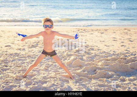 Cute smiling boy standing on the beach and holding Australian flags on Australia day Stock Photo