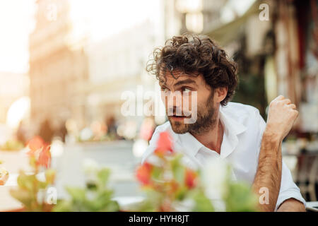 handsome masculine man sitting at terrace alone, elegant dressed, outdoor Stock Photo