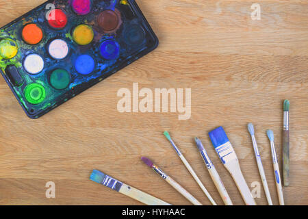 Box with watercolors and brushes on wooden surface Stock Photo