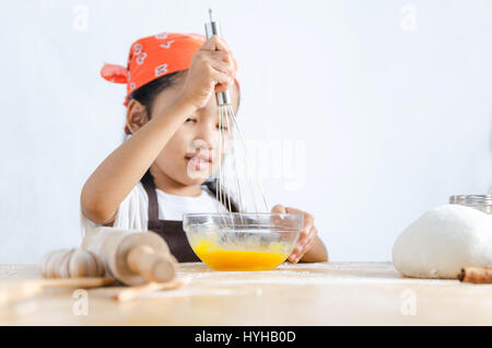 Asian little girl using stainless steel whisk to mix the egg for making bakery, select focus on hand  shallow depth of field Stock Photo