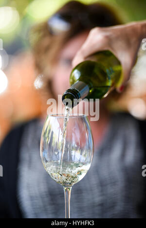 Hand pouring wine to a wine glass Stock Photo