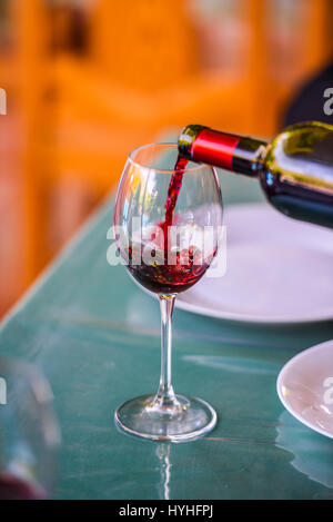 Hand holding red wine bottle and filling the glass Stock Photo
