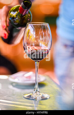 Hand holding red wine bottle and filling the glass Stock Photo