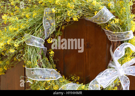 Floral wreath of May made with yellow wild flowers and white ribbon bow Stock Photo