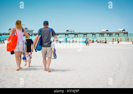 Family strolls the white sand beach near the pier at Clearwater Beach, FL, a popular vacation destination  on the west coast of South Central Florid's Stock Photo