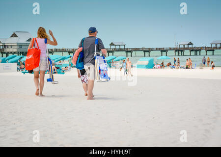 Family strolls the white sand beach near the pier at Clearwater Beach, FL, a popular vacation destination  on the west coast of South Central Florid's Stock Photo