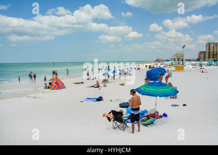 View of people enjoying the white sand and turquoise waters of Clearwater Beach, FL, with Number 5 lifeguard tower and blue cananas and umbrellas and  Stock Photo