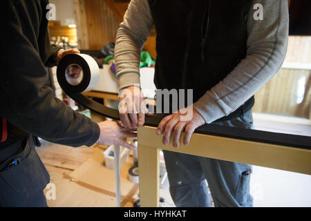 Workers preparing to install new three pane wooden windows in an old wooden house. Home renovation, sustainable living, energy efficiency concept. Stock Photo