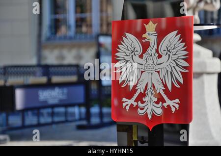 The coat of arms of Poland is a white, crowned eagle with a golden beak and talons, on a red background. Stock Photo