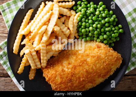 Delicious cod fish and chips with peas close-up on a plate on the table. Horizontal view from above Stock Photo