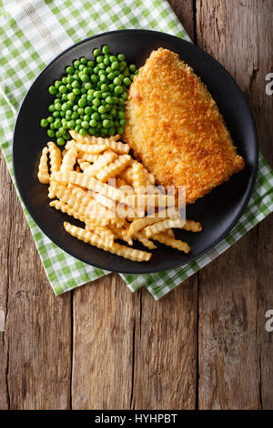 Traditional British food: Fish and chips with green peas close-up on a plate on a table. Vertical view from above Stock Photo