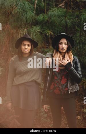 Young ethnic girls in hats modeling in front of trees. Stock Photo