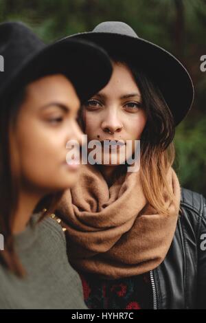 Young ethnic girls in hats modeling in front of trees. Stock Photo