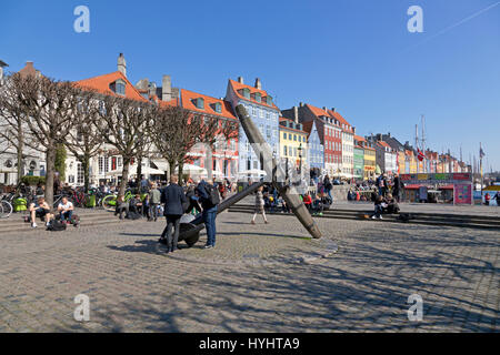Students at the Memorial Ancher in Nyhavn, Copenhagen, on a sunny day in early April. Nyhavn is a popular urban space for citizens and tourists. Stock Photo