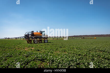 Farm machinery spraying insecticide to the green field. Stock Photo